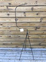 Front view of full wrought iron tripod hanger against wooden fence