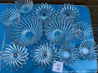 Full display of 11 glass flower-shaped dishes including two large bowls, four plates, and five smaller bowls on a blue table.