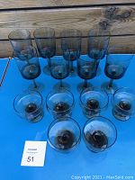 Top frontal view of 8 wine glasses and 6 champagne glasses arranged on blue surface with wooden textured background.