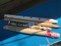 Four rolled wallpaper pieces in various patterns and colors laid on a blue surface outdoors.