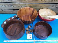 Photo of four wooden bowls, wooden candle holder with four tea light holders, four small striped wooden salt cellars, and wooden tongs arranged on blue surface with ruler for size reference.