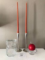 Wide view of the set showing all items including the two Dansk metal taper candleholders with orange candles, glass jar, round glass candleholder with red candle.
