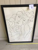 Full front view of framed print leaning against wall, showing overall condition and scale with measuring tape.