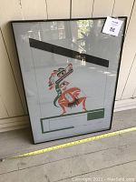 Framed silkscreen print of Native art from Pacific Northwest Coast Canada by Art Thomson, placed leaning against a wall, showing its condition and size next to a measuring tape.