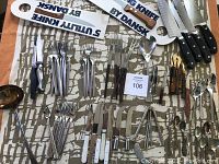 Full overview of midcentury flatware and knives laid out on patterned surface