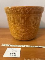 Front side view of large yellow Roseville planter with basket weave texture and ruler showing size
