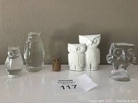 Front view of six owl figurines on shelf showing variety in size, material, and style.