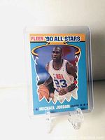 Front view of Fleer 1990 Michael Jordan All-Star card in a clear protective plastic case on a stand.