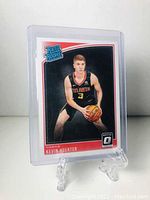 Front of Kevin Huerter rookie basketball card in protective sleeve on display stand showing player image and card branding.