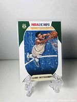 Front side of the Giannis Antetokounmpo NBA Hoops trading card showing the player dunking the basketball in Milwaukee Bucks uniform with NBA Hoops and team logo visible.