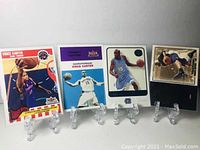 Four Vince Carter basketball cards arranged in a row on small clear stands.