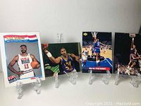 4 Karl Malone basketball cards shown on clear display stands, featuring different themes including 1992 USA Basketball Team and NBA All-Star Heroes.