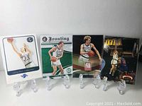 Front view of all four Larry Bird basketball cards displayed on clear stands.