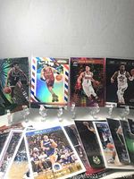 Display of 8 basketball cards on clear stands showing various players and holographic effects including Jamal Murray and others.