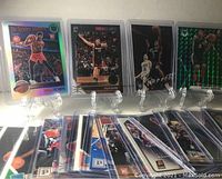 Group of 20 NBA rookie cards displayed standing and lying flat, showing front sides of the cards. Includes visible player images and holographic card designs.