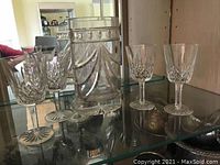 Photo showing the set comprising four Waterford stemmed wine glasses and one Waterford vase on a glass shelf with reflection and background.