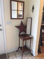 Overall view of wooden entry table with windowpane mirror, metal star, and 'Welcome' sign arranged on and near the table.