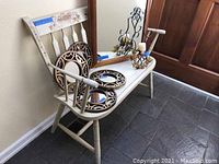 Wood bench with floral decoration, holding four round decorative mirrors and metal candle holder.