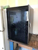 Front view of black Magic Chef wine cooler with closed glass door and metal handle.