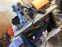 Photo of Craftsman fixed base router mounted on router table with electrical cords and accessories around, showing tools and some paperwork.
