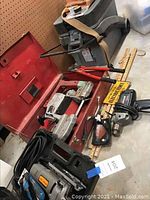 Display of power tools including jigsaw, drill, band saw, bolt cutters, and tool cart.