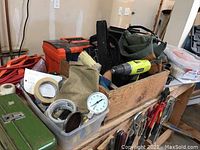 Photo illustrating toolboxes, tape rolls, PSI test gauge, drill, and assorted tools in containers