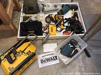Wide view of the lot showing DeWalt drill, carry case, clamps, hand tools and bags.