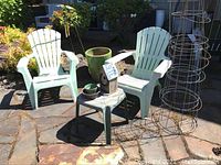 Overview of all patio furniture and garden decor including two plastic chairs, glazed pot, small table, birdhouse, tomato cages