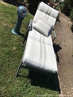 Photo showing garden lounger with adjustable backrest, removable cushions and pillow placed on grass next to gazing ball stand.