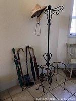 Full view of metal coat rack with canes and umbrellas arranged around base, cowboy hat on top hook
