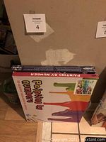 Photo of two unopened paint by numbers kits stacked, one abstract paint splash, one visible PaintWorks Whales kit