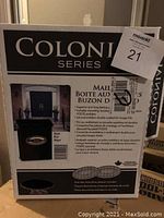 Photo of unopened box showing brand Colonil Series and mailbox details including mounting hardware, lid, and emblem.