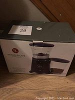 Boxed black and clear electric coffee grinder with control dial and collection container attached to the side, brand Moulin à Café