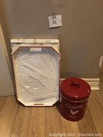 Photo showing red and white vintage serving tray in original box with wrapping alongside a red canister.