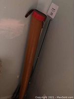 Photo showing tan carrying case with red top and a fishing rod leaning against wall