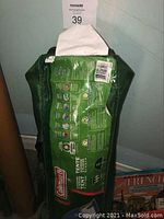 Photo showing the green Coleman tent storage bag with detailed product features and barcode.