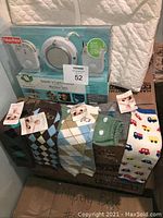 Packaged Fisher-Price Sounds'n Light monitor and seven pairs of baby leg warmers displayed on boxes. Various patterned leg warmers are shown including argyle designs and vehicles.