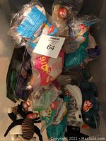 Photo showing a collection of 24 Ty Beanie Babies still in individual plastic packages, some clearly McDonald's branded, various animal characters visible including penguin and tiger.