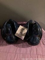 Pair of blue ceramic swan planters placed side by side, showing front and wing details with a tag in between.