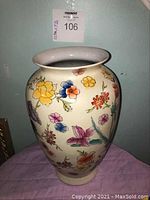Front view of oval-shaped Chinese ceramic vase with colorful floral hand-painted decoration and a wide flared rim.