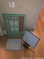 Turquoise compartment frame leaning against the wall next to two square Buddha boards and a wooden board holder on the floor