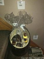 Full view of the gift basket wrapped with transparent plastic film and tied with white ribbon, showing six body care items inside.