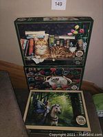 Stack of three Cobble Hill puzzle boxes featuring images of cats and a fantasy unicorn scene.