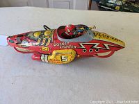 Left side view showing pilot, ‘Rocket Fighter’ text, number ‘5’ and wear to lithograph