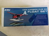 Photo of the boxed E-flite UMX Carbon Cub SS Float Set with image of red and white floats on packaging and product details.