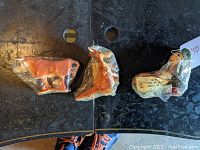 Three vintage Marx ramp walker toys lying side by side on a surface still wrapped in their original clear cellophane. Left is a brown bull, middle is a kangaroo with joey, right is Jiminy Cricket with wheelbarrow.