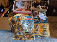 Overview of multiple vintage plastic toy sets including boxed and carded sets with various figures and accessories.