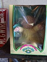 Front view of 1985 Coleco Cabbage Patch Kid doll inside original box with visible tag and outfit