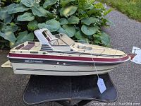 Side view of the beige and maroon Vee Sport 2660 RC motorboat showing detailed deck features and railing.