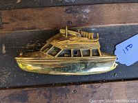 Front view of solid brass door knocker shaped like a boat, showing detailed windows and roof rack with equipment on top.
